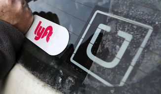 In this Jan. 31, 2018, file photo, a Lyft logo is installed on a Lyft driver's car next to an Uber sticker in Pittsburgh. On Monday, Aug. 10, 2020, a California judge ordered ride-hailing companies Uber and Lyft to treat their drivers as employees, not contractors. On Aug. 20, 2020, an appeals court issued an injunction allowing the companies to continue operating as usual pending outcome of the appeal by Uber. (AP Photo/Gene J. Puskar, File) **FILE**