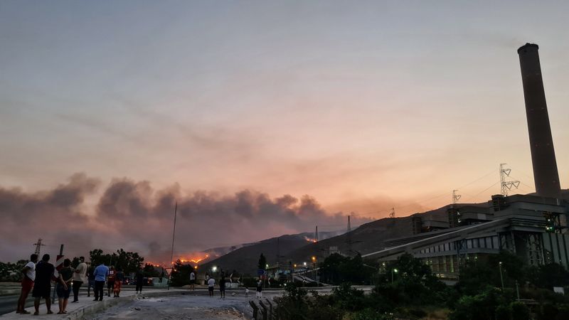 Flames and smoke fill the sky as residents watch the wildfire near Cokertme