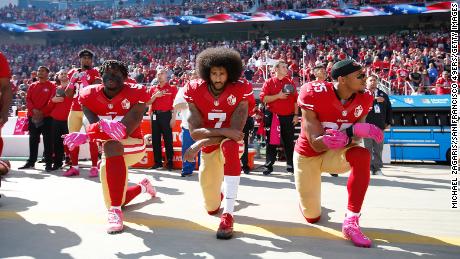 Colin Kaepernick, center, and two other members of the San Francisco 49ers kneel during the national anthem prior to a game against the Tampa Bay Buccaneers on October 23, 2016, in Santa Clara, California. 