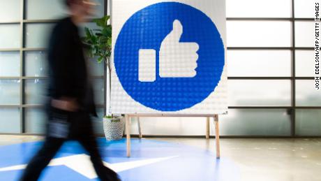 A Facebook employee walks by a sign displaying the &quot;like&quot; sign at Facebook's corporate headquarters campus in Menlo Park, California, on October 23, 2019. (Photo by Josh Edelson/AFP/Getty Images